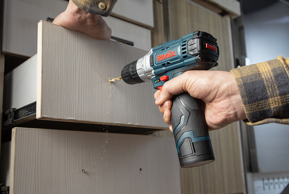 Drilling holes with a drill to attach handles to a drawer