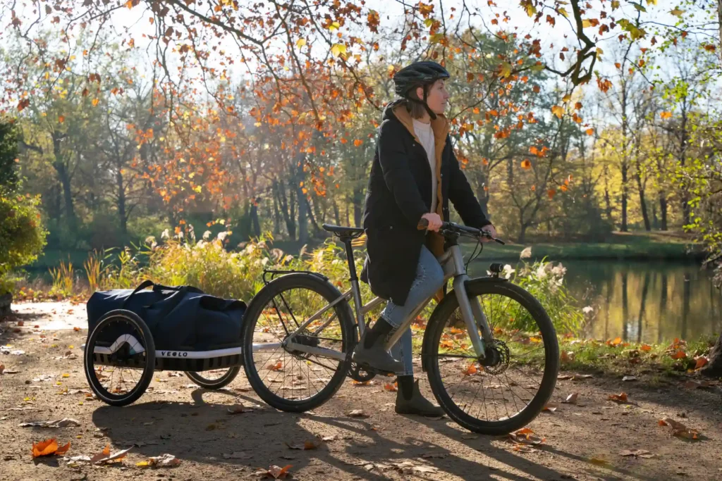 fahrradfahrerin mit veolo bike trailer im park, fahrradanhänger schloss