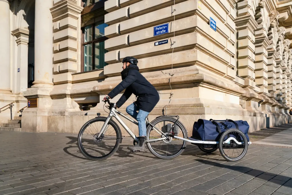 fahrradfahrerin mit fahrradanhänger in der stadt, fahrradanhänger schloss