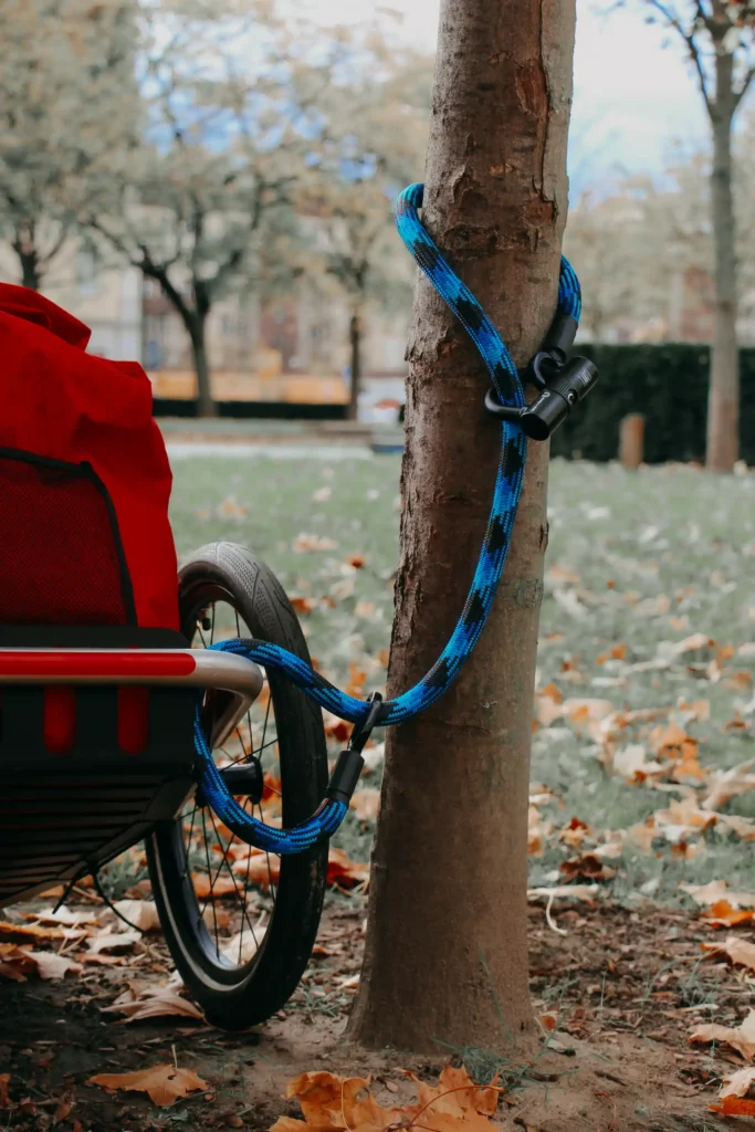 fahrradanhänger mit roter tasche am Baum angeschlossen mit blauem  Textilschloss, fahrradanhänger schloss