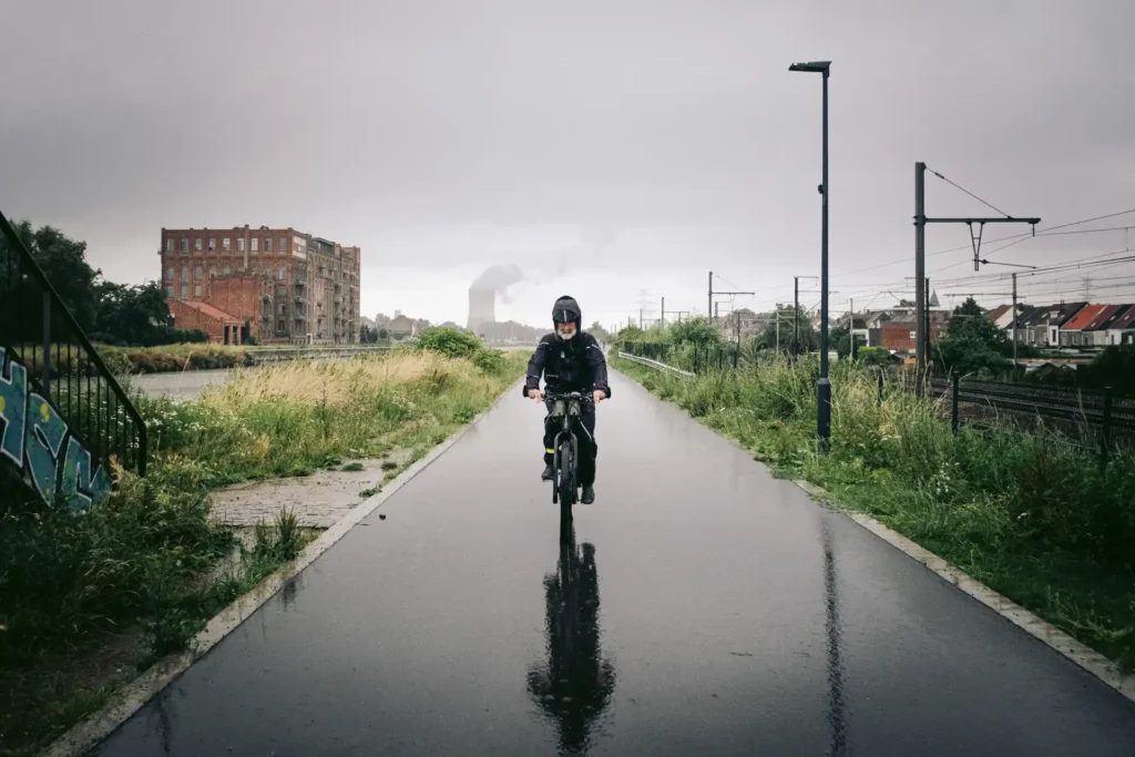 Fahrradfahren im Regen auf nasser Straße mit Fahrrad Regenbekleidung