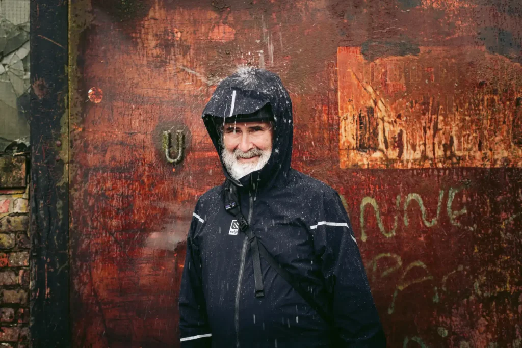 Herr in Fahrrad Regenjacke mit Kapuze und Regenschild auf das Wasser tropft