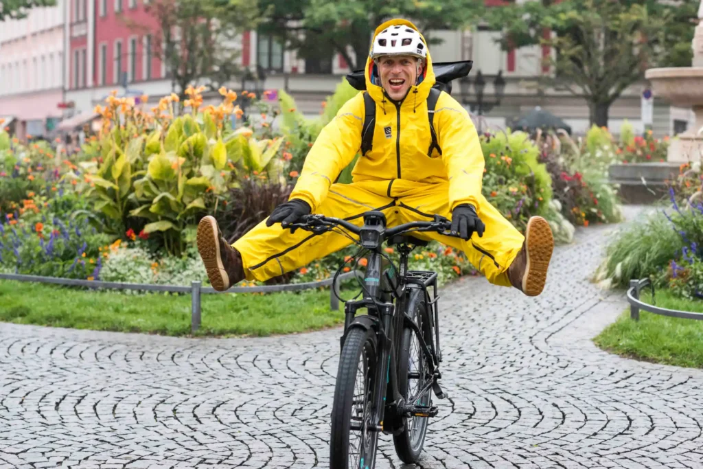 Lachender Mann in gelber Regenbekleidung beim Fahrradfahren im Regen